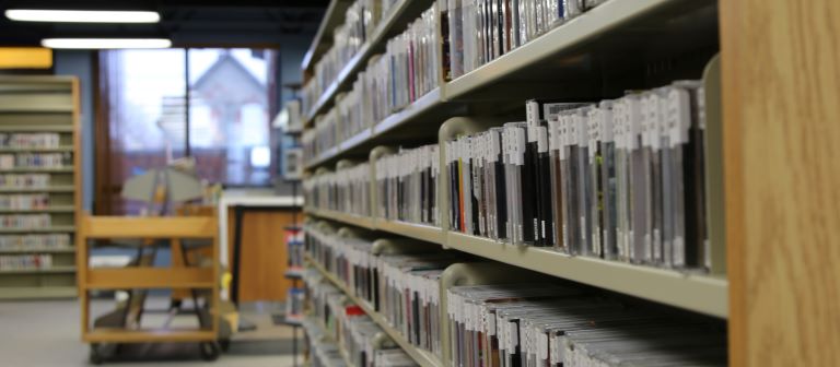 A photo of a shelf of CD cases with their spines facing out.